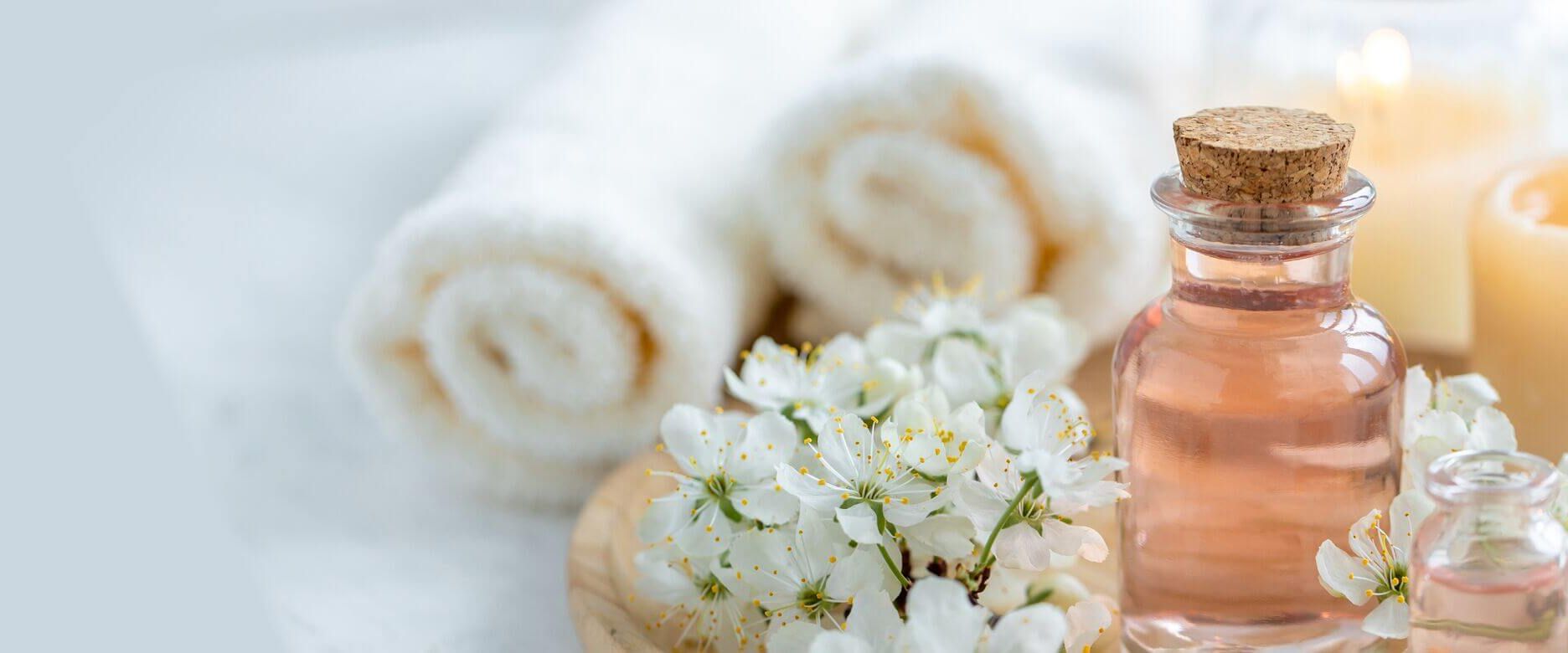 Ein elegantes Arrangement aus Babor-Fläschchen, weißen Blüten und Kerzen vermittelt eine entspannende Kosmetikstudio-Atmosphäre.