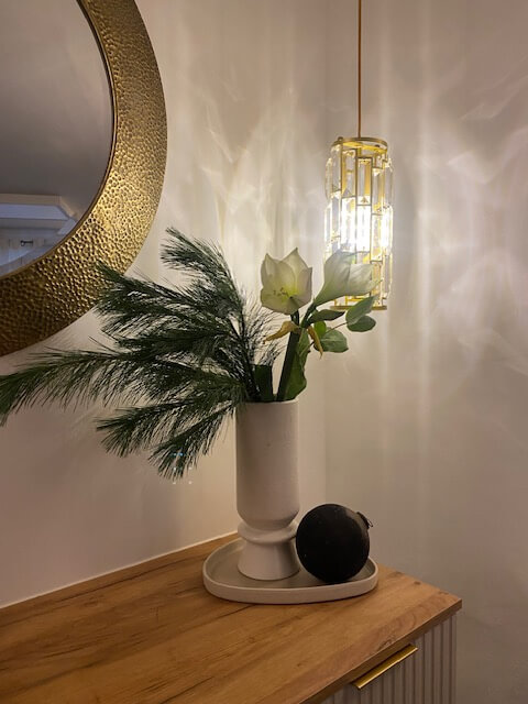 Ein stilvoller Tisch mit Vase und Dekorationen beleuchtet von einer eleganten Lampe, ideal für ein Kosmetikstudio.