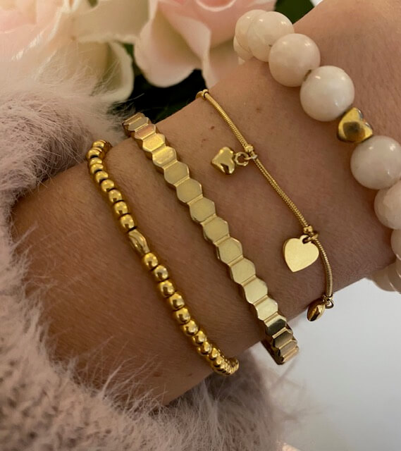 Eine Hand trägt stilvolle goldene Armbänder, die Eleganz und Kosmetik inspirieren.