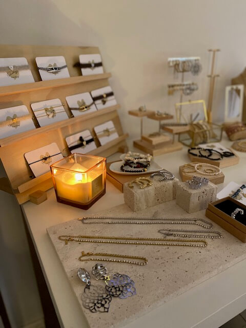 Ein stilvoll dekorierter Tisch mit Schmuck und einer brennenden Kerze schafft eine einladende Atmosphäre wie in einem Kosmetikstudio.