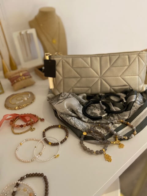 Auf einem Tisch im Kosmetikstudio liegen Armbänder, eine Tasche und ein Tuch dekorativ arrangiert.